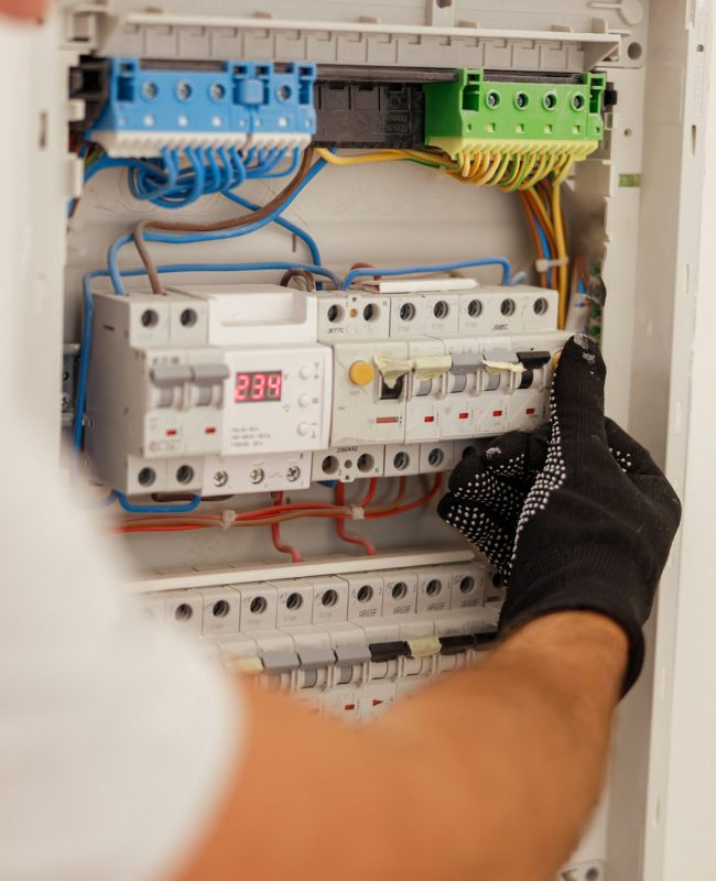 Hand of electrical technician working with fuses at the circuit breaker control cabinet on the